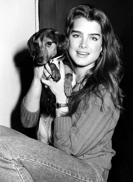 black and white photo of Brooke Shields holding her Dachshund with her two hands