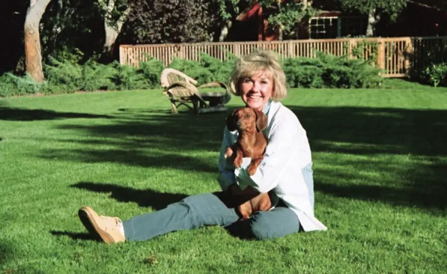 Doris Day sitting on the green grass with her Dachshund