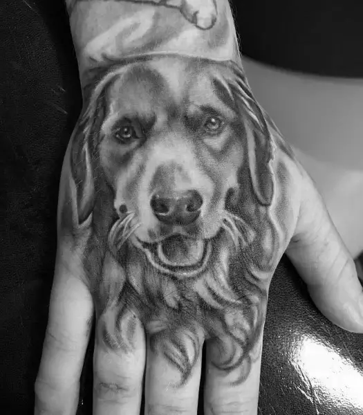 black and white photo of 3D smiling face of Golden Retriever Tattoo on hand