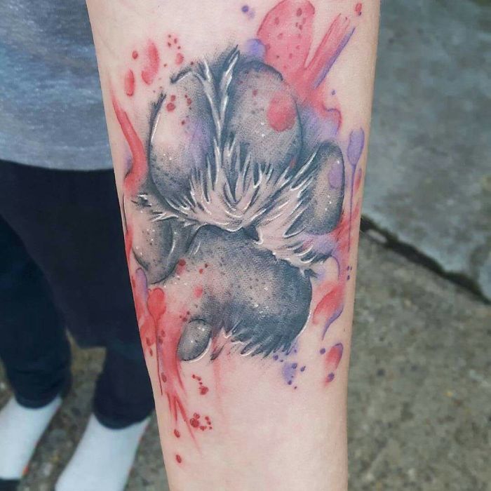 large 3D paw print tattoo with splash of watercolor tattoo on arm