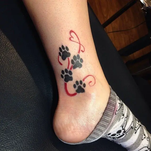 four paw print tattoos with red heart lines on the ankle