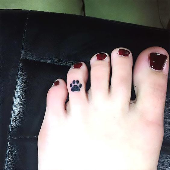 small paw print tattoo on the ring finger on feet