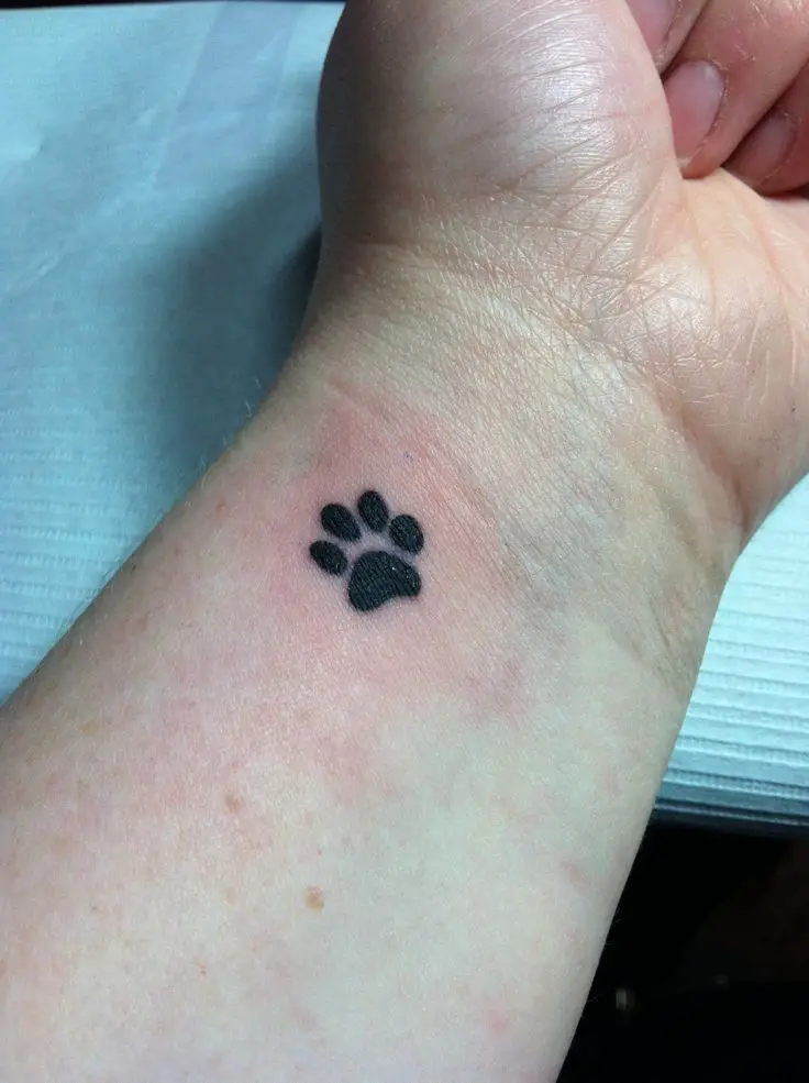 small minimalist paw print tattoo on the wrist