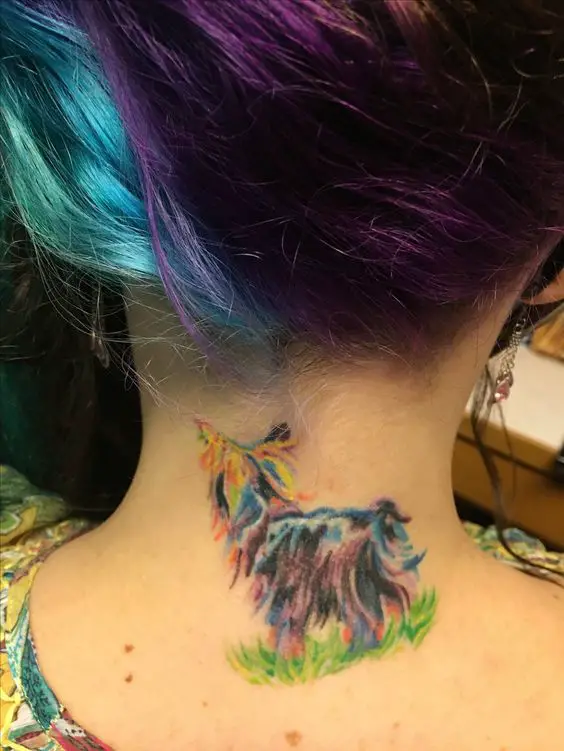a colorful yorkie standing on the green grass tattoo on the back of the girl's neck
