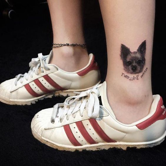 a minimalist face of a black yorkie tattoo on the ankle