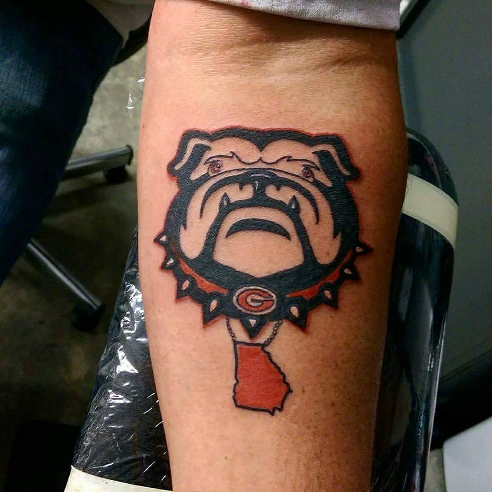 animated angry face of English Bulldog wearing a collar with horns tattoo on forearm