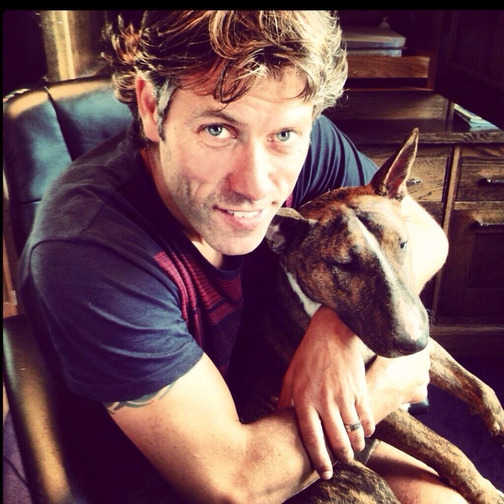 John Bishop sitting on the chair with his English Bull Terrier in his lap