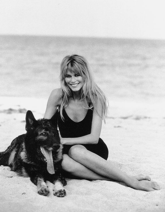 Claudia Schiffer sitting in the beach with her German Shepherd