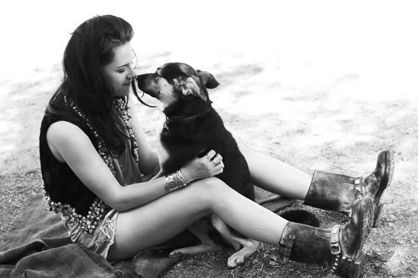 Kristen Stewart sitting in the sand while kissing her German Shepherd puppy