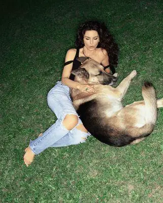 Shania Twain lying on the green grass with her German Shepherd