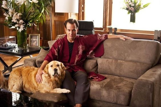 Will Arnett sitting on the chair behind his Golden Retriever standing on the floor