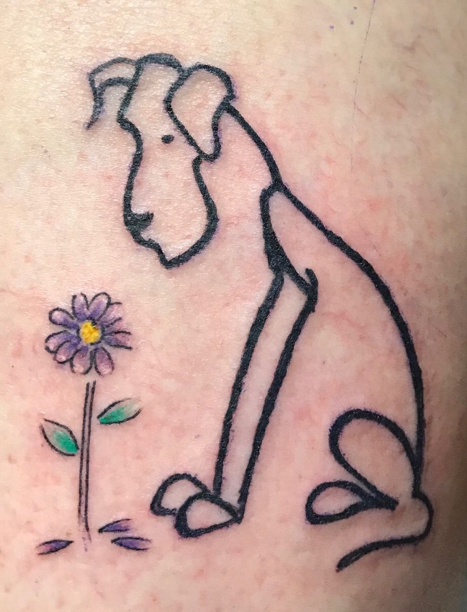 outline tattoo of a Great Dane sitting while looking at a purple flower