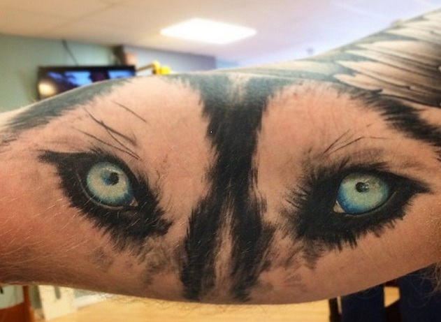 blue eyes of a Husky tattoo on the forearm