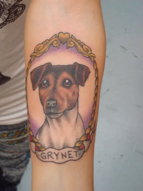 sweet face of a Jack Russell Terrier inside a vintage frame tattoo on the forearm