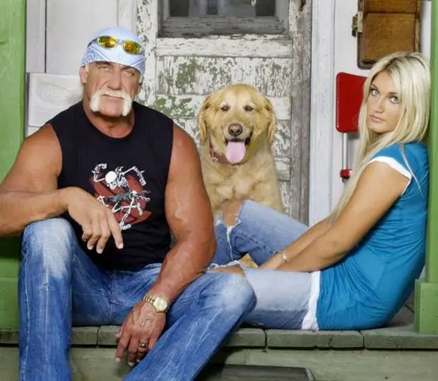 Hulk sitting on the wooden floor with a woman and their yellow Labrador Retriever sitting in between them