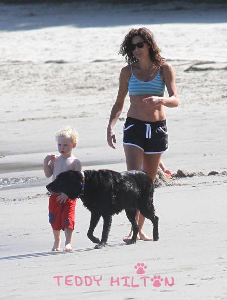 Minnie Driver walking in the sand at the beach with her Labrador Retriever named Bubba and her kid
