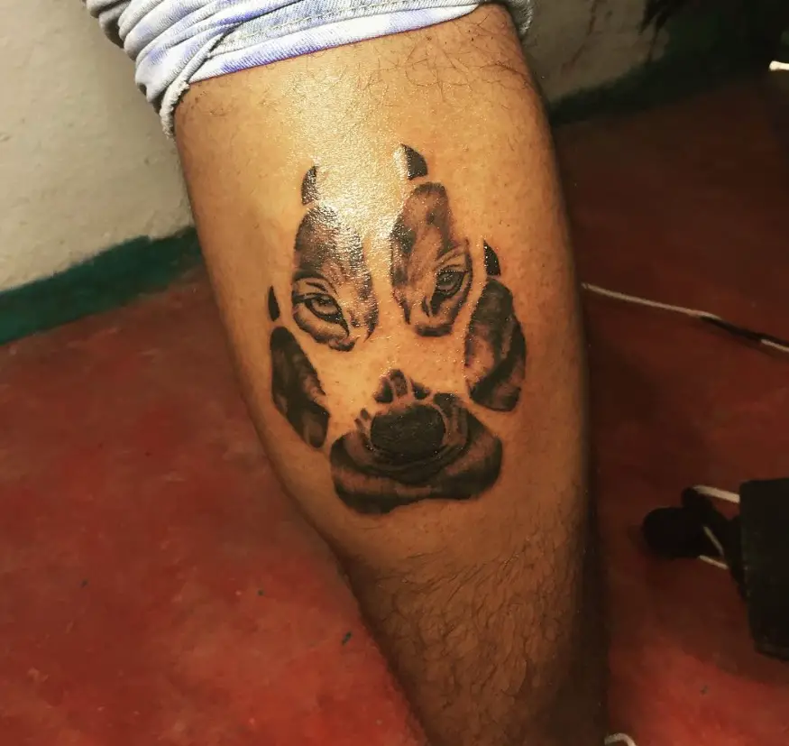 large paw print with the face of a husky tattoo on the leg