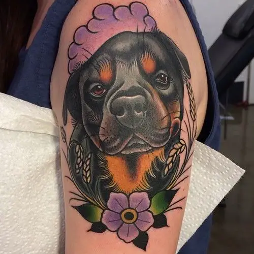 animated adorable face of Rottweiler Tattoo with purple flowers and green leaves tattoo on the shoulder