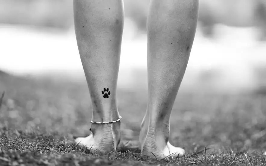 small paw print tattoo on the back of the ankle