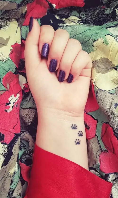 three paw print tattoo on the wrist of the woman