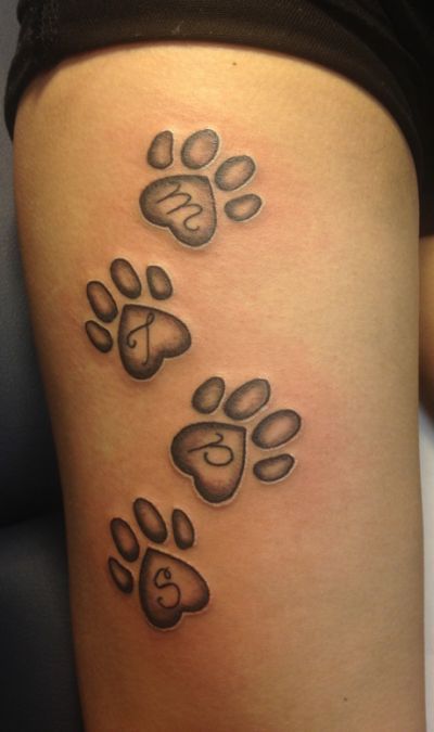 four 3D paw print with initial inside tattoos on the thigh