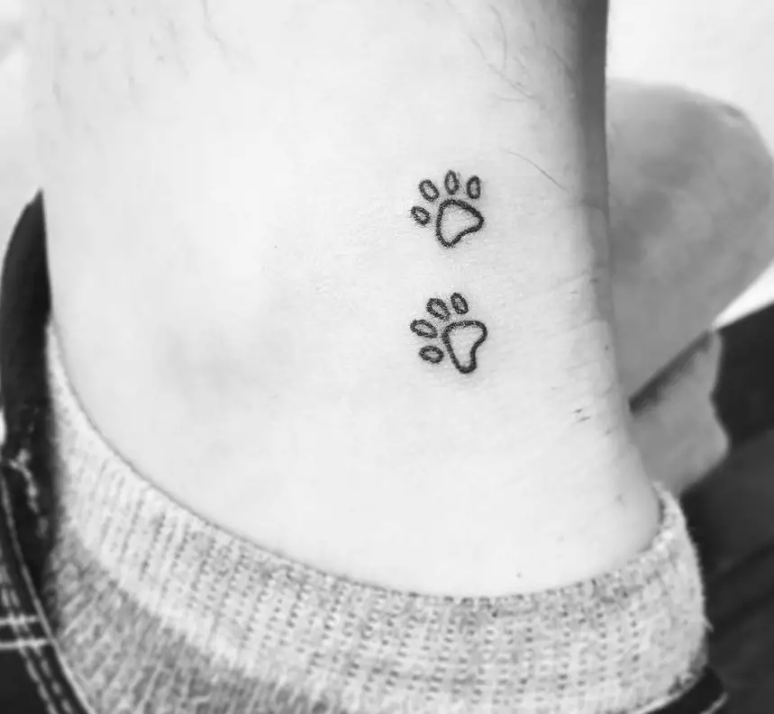 small outline paw print tattoo on the ankle