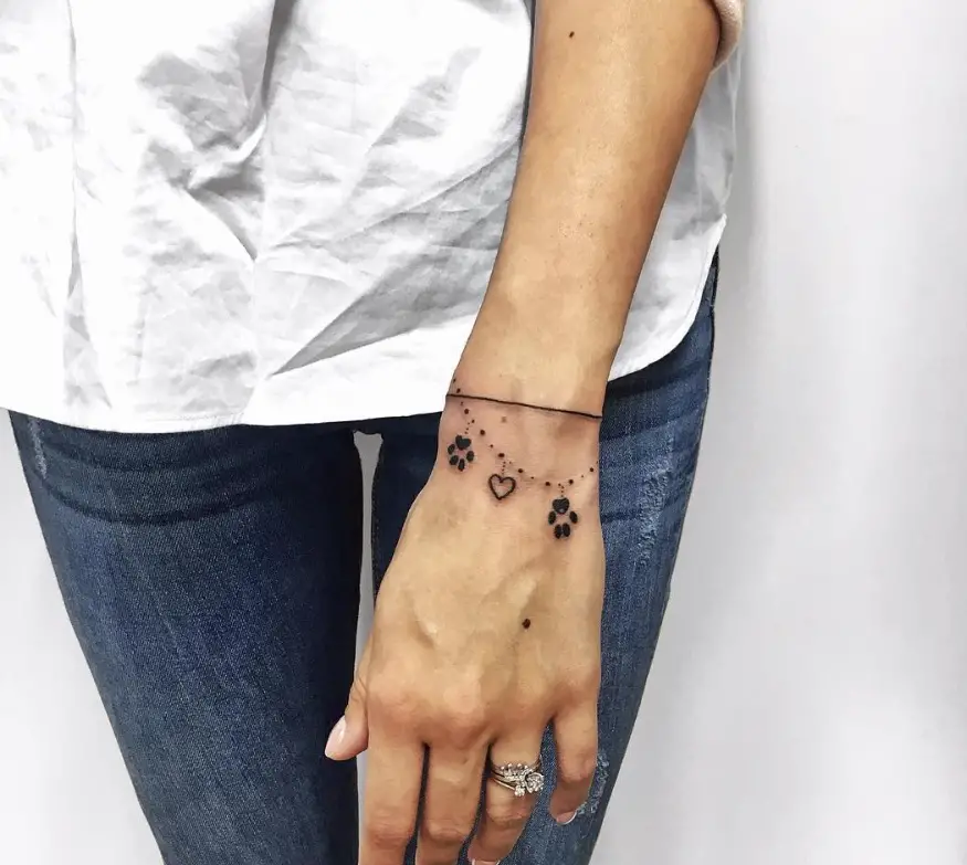 paw print bracelet tattoo on the wrist of a woman
