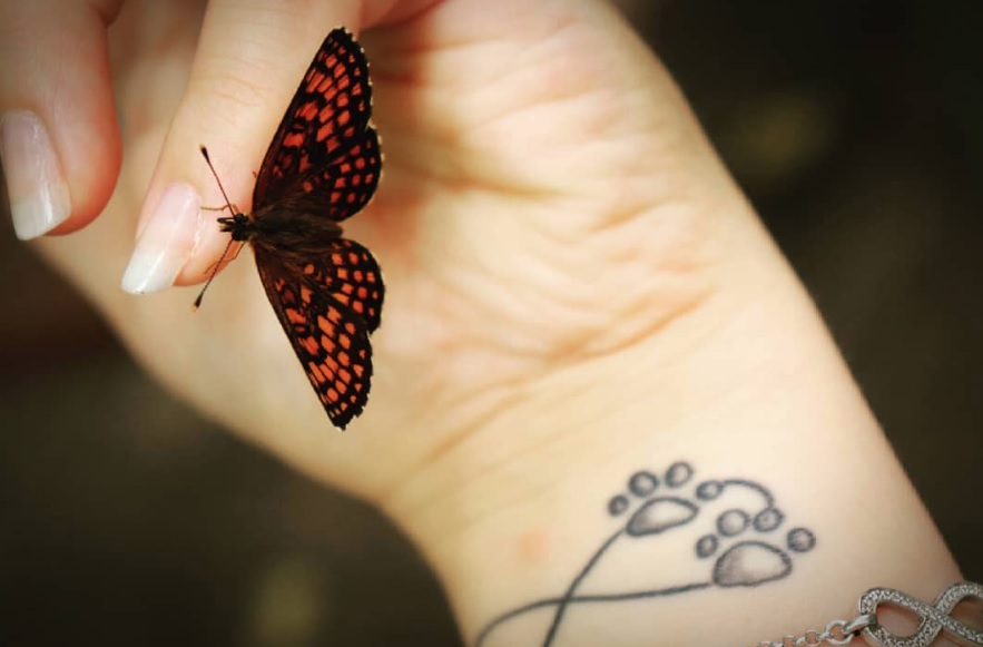 heart sign with paw print tattoo on the wrist