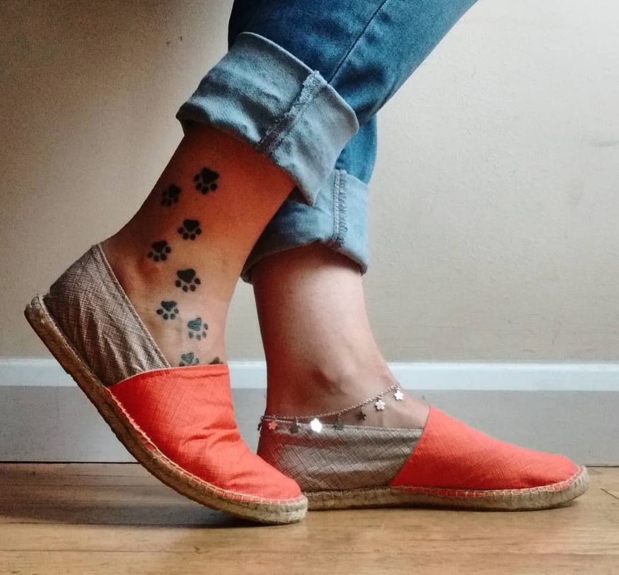 eight small paw prints tattoo on the leg of the woman