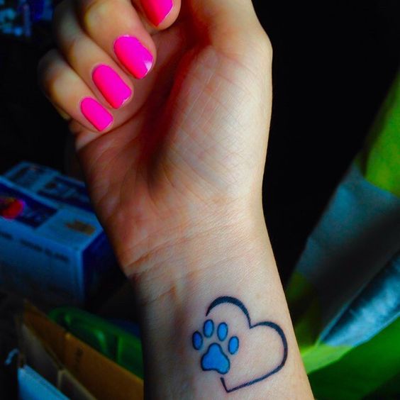 a heart outline with a blue paw print tattoo on the wrist