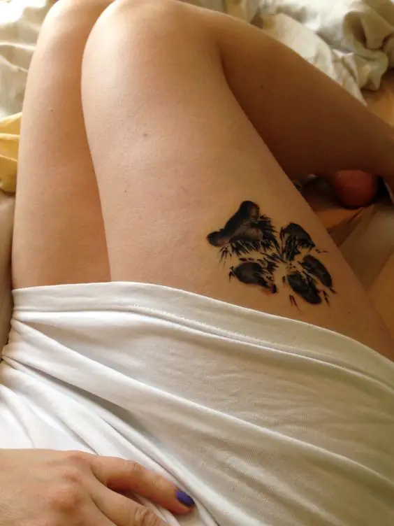 a 3D paw print tattoo on the thigh of the woman lying in bed