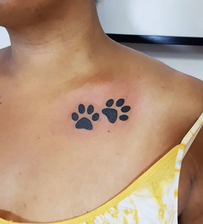 two paw prints tattoo on the collar of the woman
