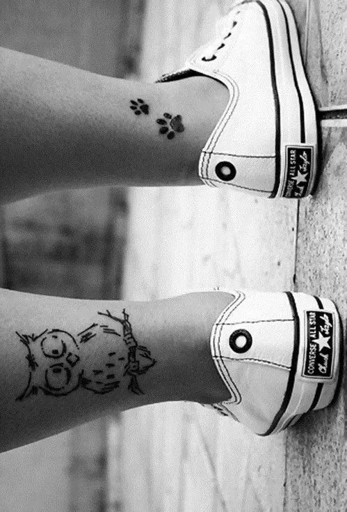 two paw prints tattoo on the ankle of the woman