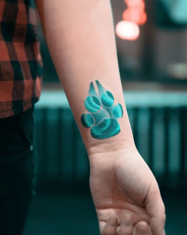 a paw print with bright blue color tattoo on the wrist