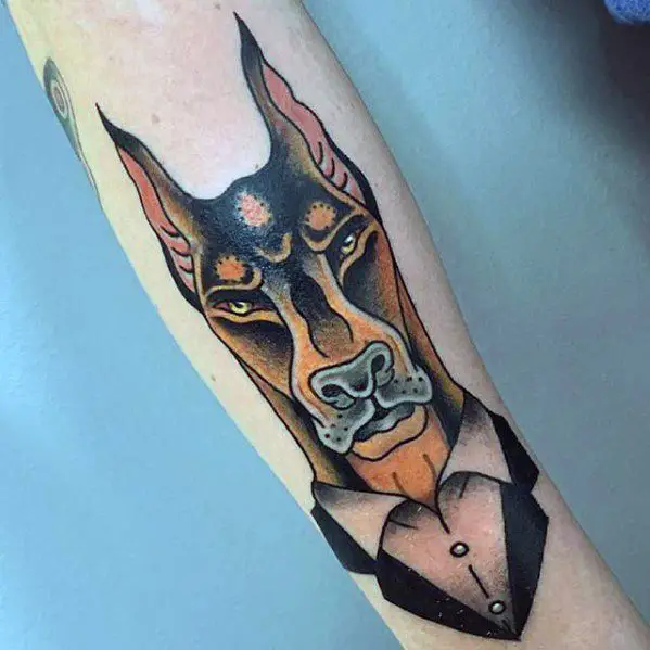 artistic suspicious face of a Doberman tattoo on the forearm