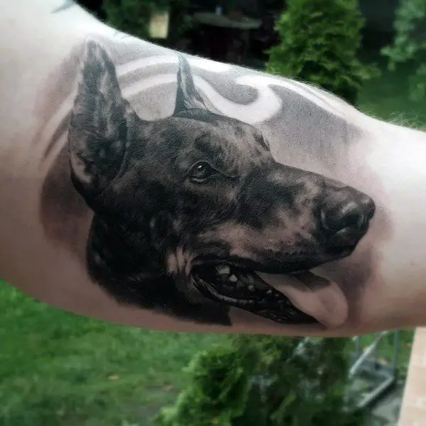 3D black and gray sideview face of a Doberman tattoo on the biceps