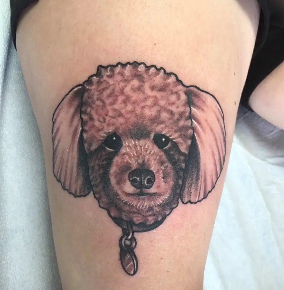 A black and gray face of a Poodle puppy tattoo on the thigh