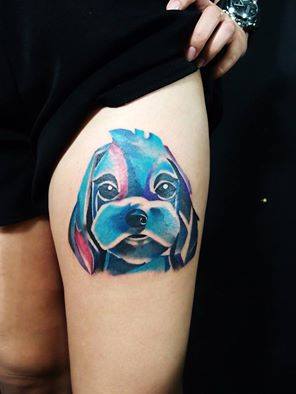 An artistic face of a Poodle puppy with blue and pink colors tattoo on the thigh