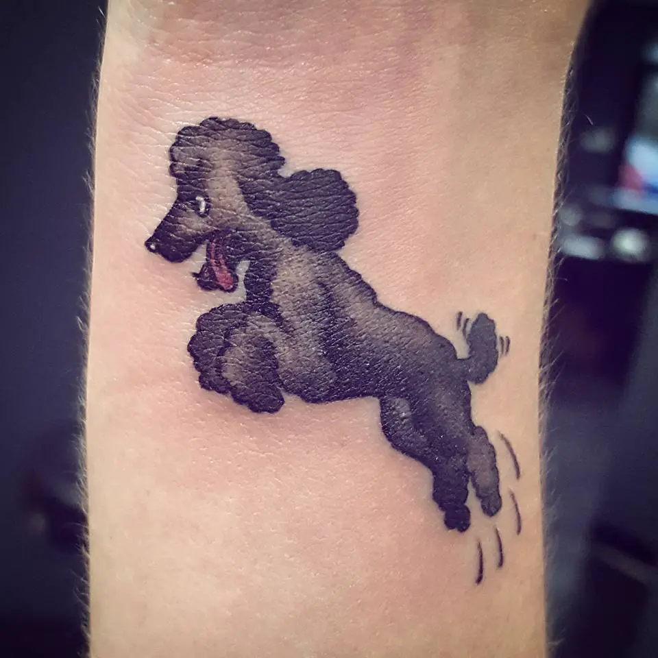 A jumping black poodle tattoo on the wrist