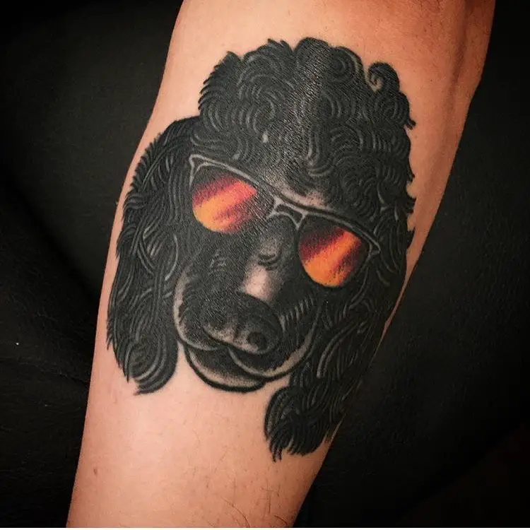 Face of a black Poodle Dog wearing sunglasses tattoo on the forearm