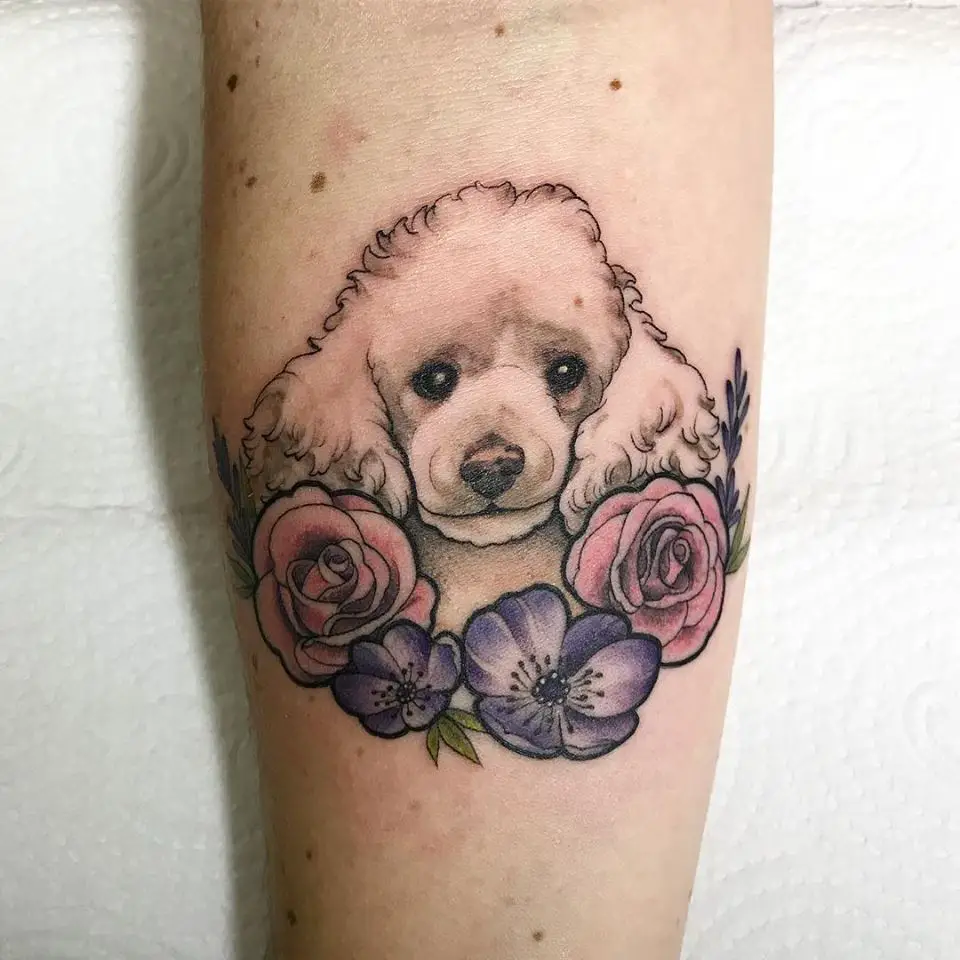 A white Poodle Dog Tattoo with pink and purple flowers tattoo on the forearm