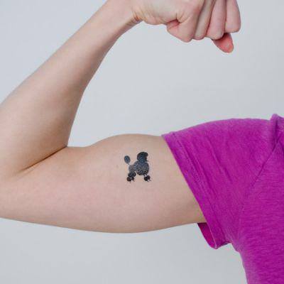 A minimalist black poodle tattoo on the biceps