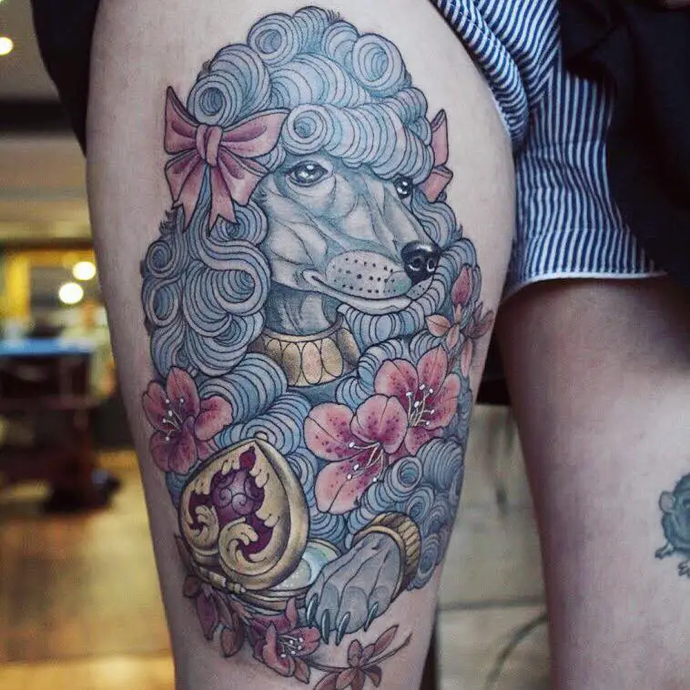 A stylish Poodle tattoo with wearing pink ribbons and with pink flowers while wearing gold accessories tattoo on the thigh