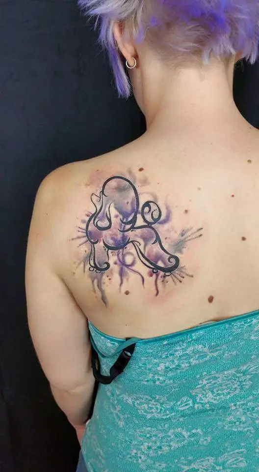 An outline of a standing poodle with purple splash of watercolor tattoo on the back of the woman