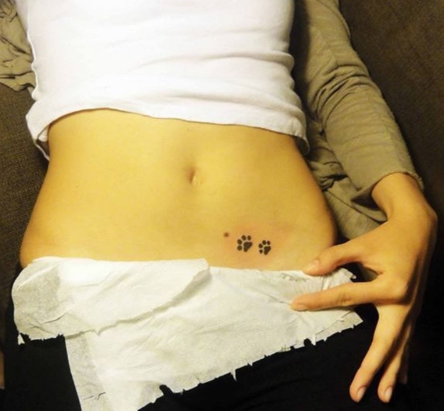 two paw prints tattoo on the lower stomach of the woman