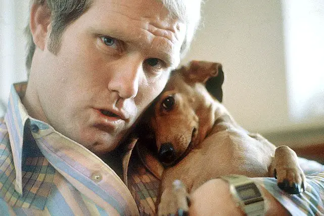 Terry Bradshaw holding his Dachshund on his chest