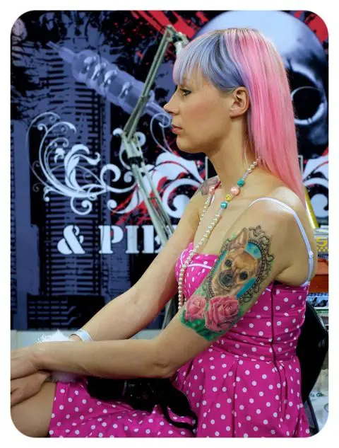 a woman in pink pulka dots dress with Chihuahua in vintage frame tattoo on her arm