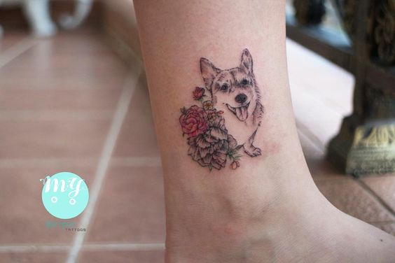 a corgi beside the flowers and leaves tattoo on the ankle
