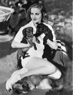 Carole Lombard sitting on the floor with her two Dachshunds in her arms
