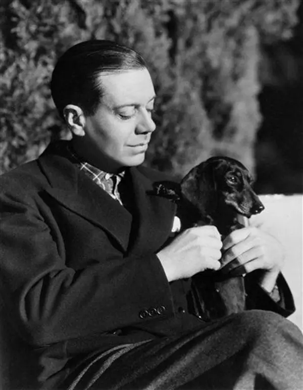 black and white photo of Cole Porter with his Dachshund sitting in his lap